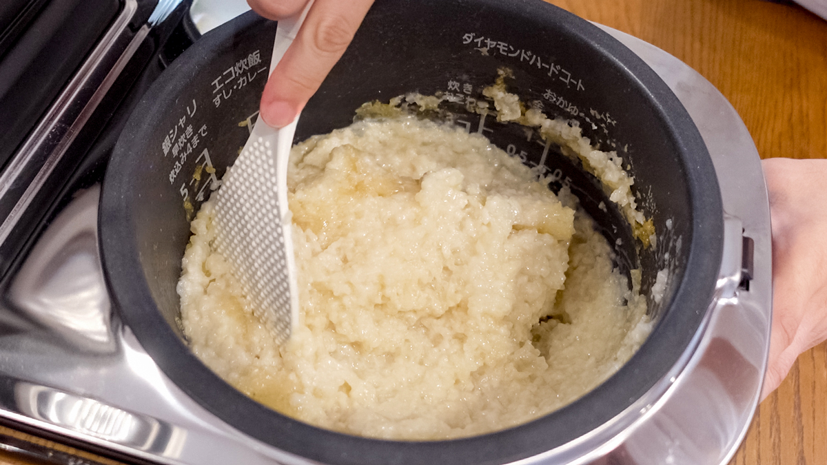 炊飯器に入った甘酒を混ぜている